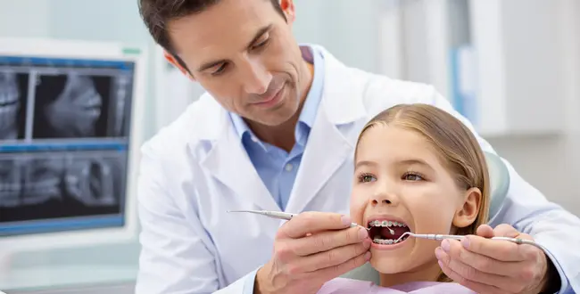 A dentist installs braces on a girl